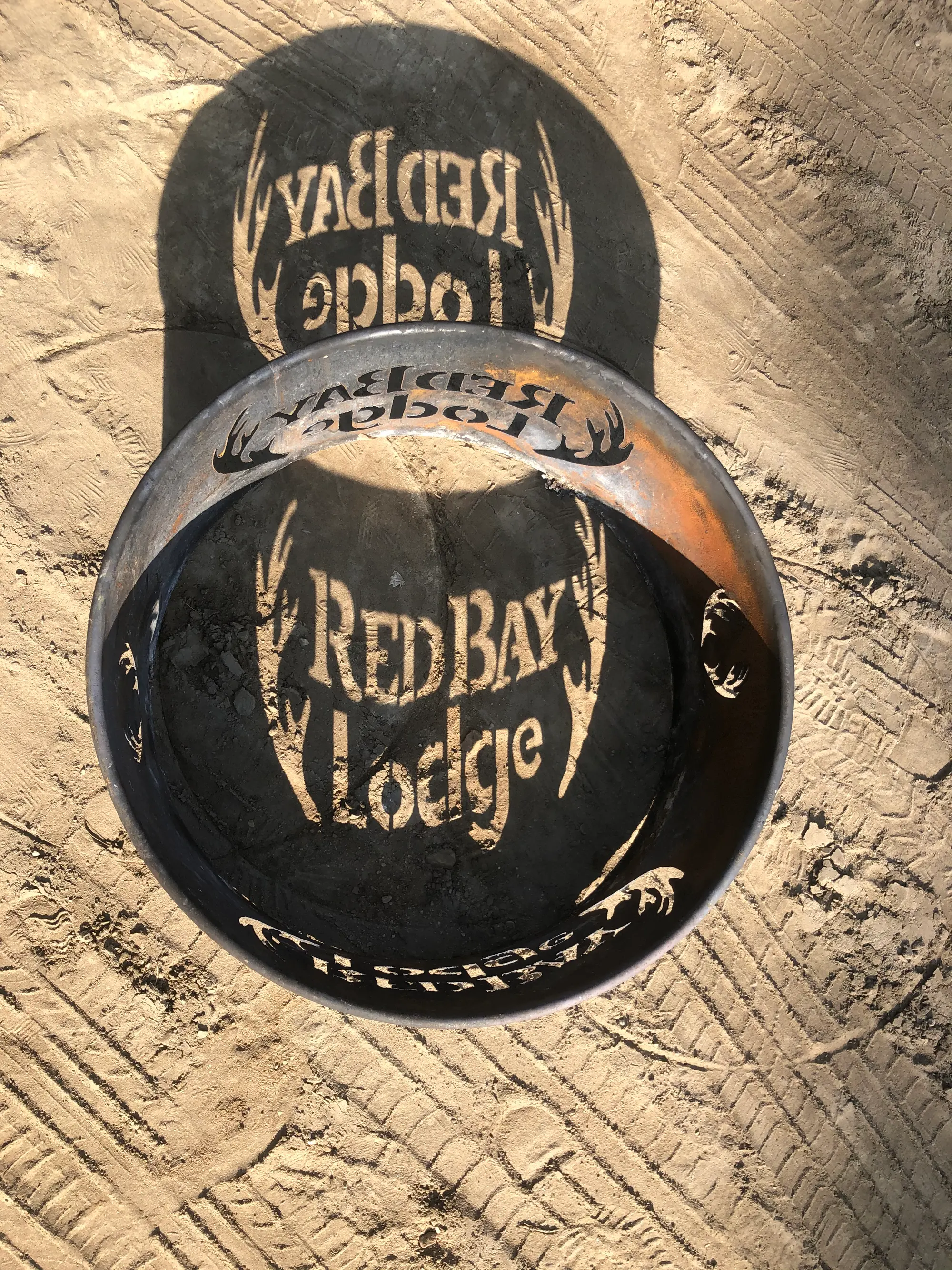 The Red Bay Lodge logo cut into a steel fire ring at the firepit