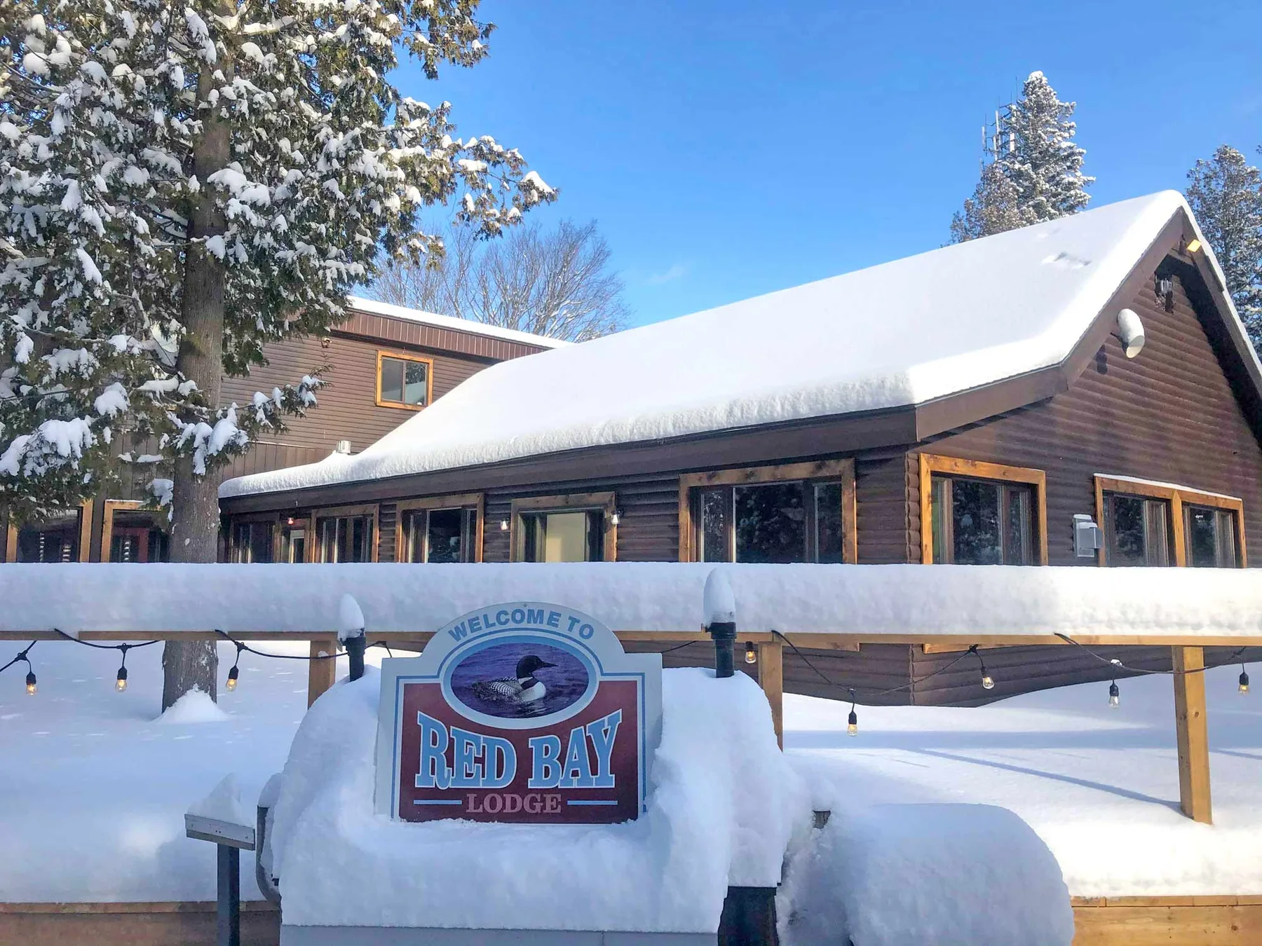 Red Bay Lodge in winter, deep snow on the roof and the lodge sign