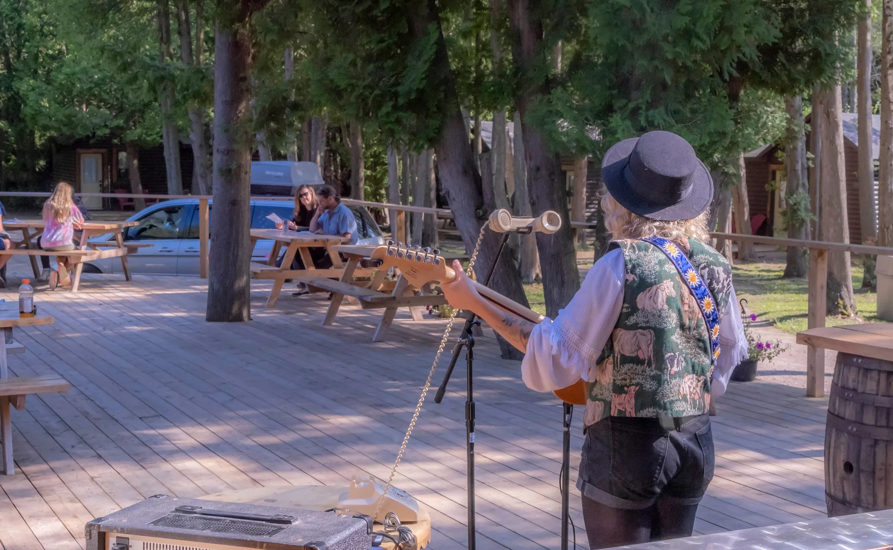 A musician performing on the lodge patio among the trees