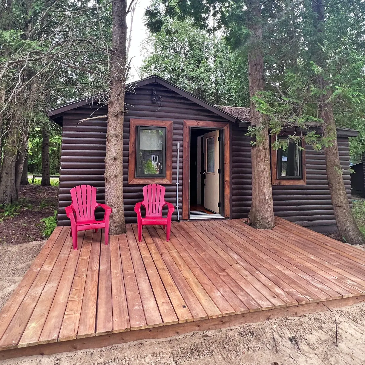The Tamarack, a 1+ bedroom cabin, with a wide deck and two red chairs