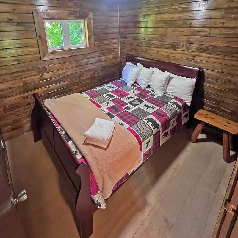 A bed with a plaid quilt in the pine-panelled Red Cedar
