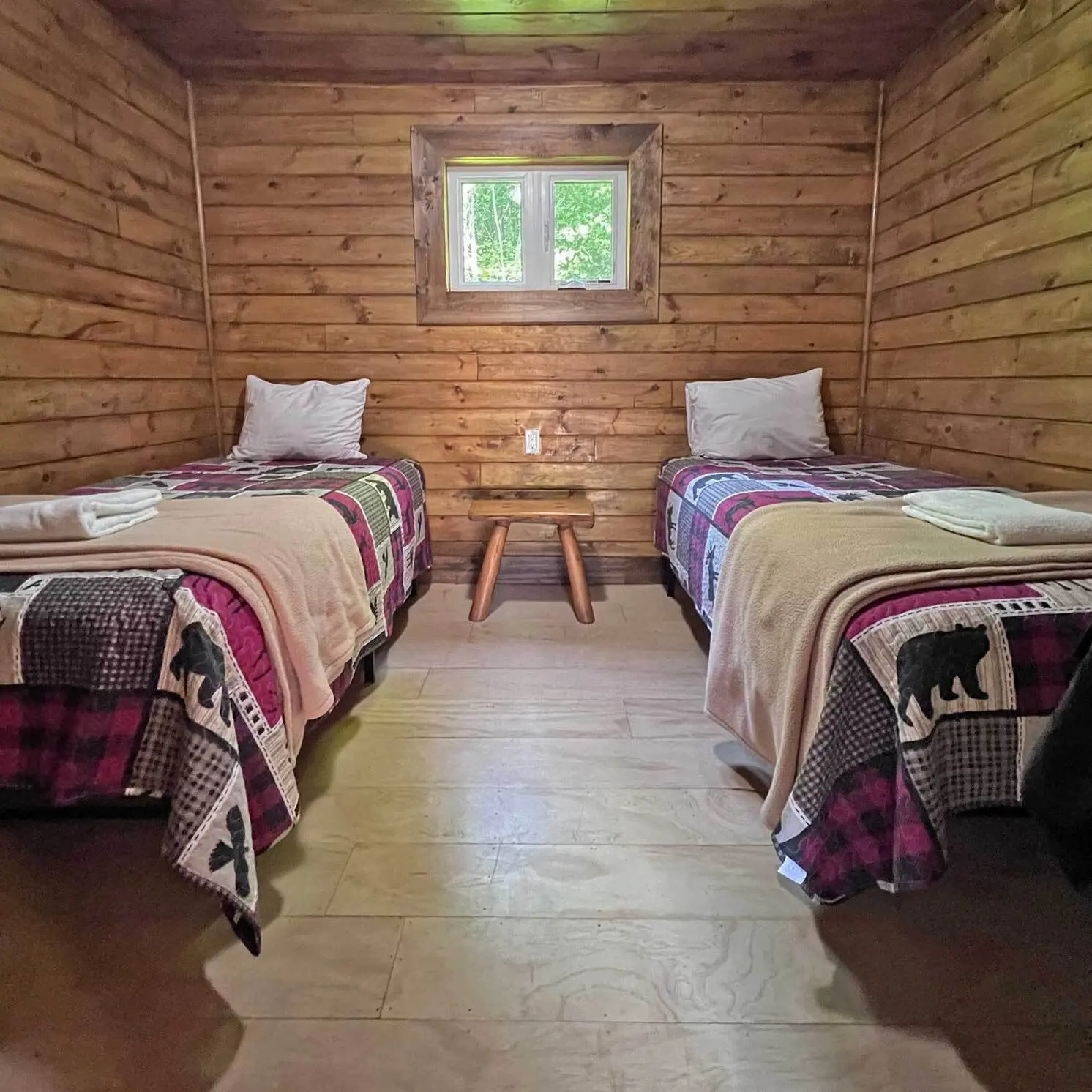 Two single beds under a window in a bedroom of the Red Cedar