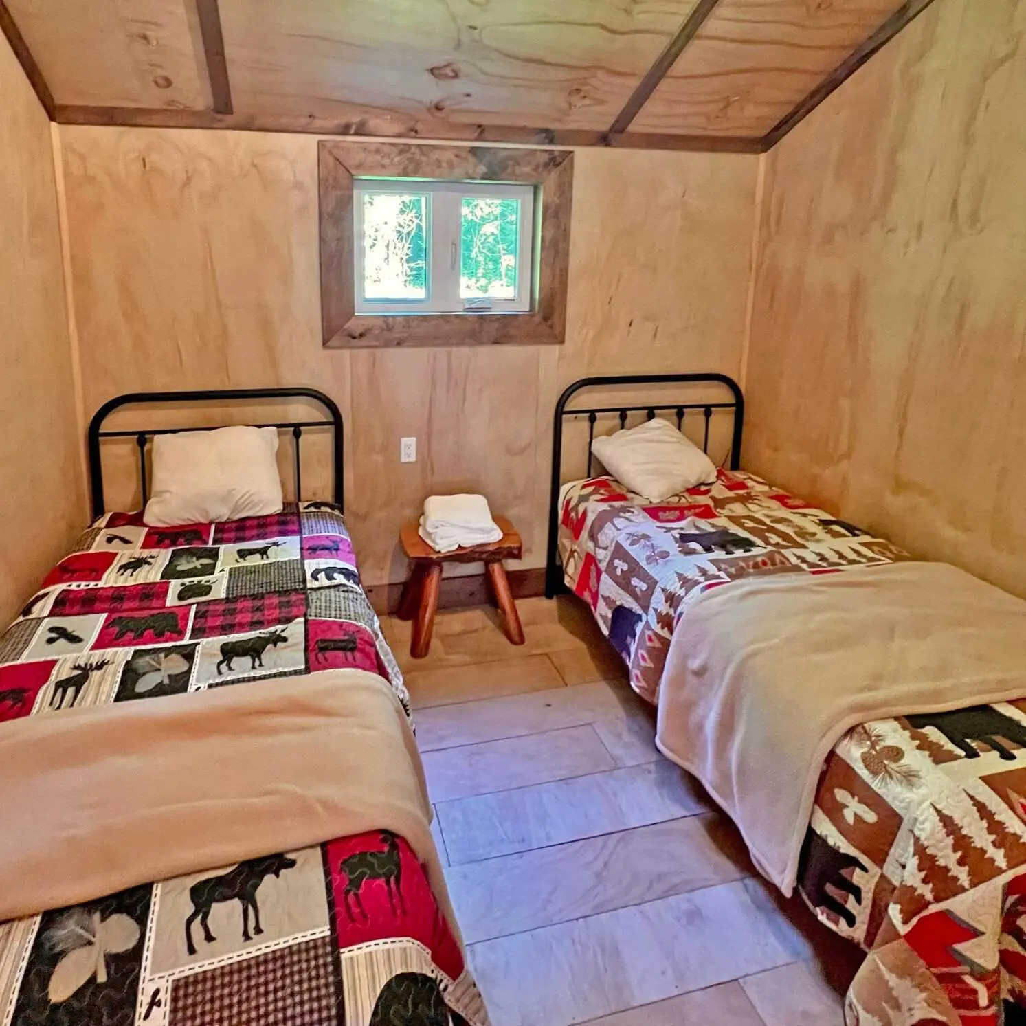 Two single beds with plaid quilts in a bedroom of the White Cedar