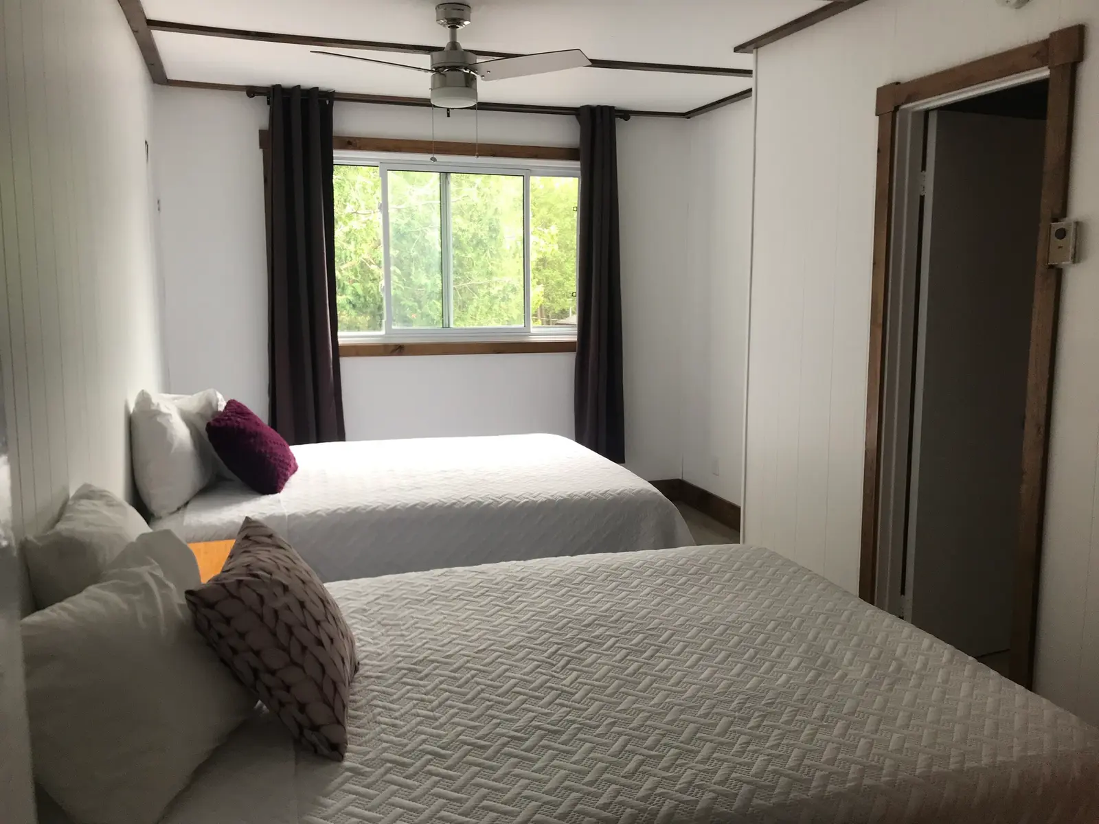 Two double beds in a bright lodge room with a window onto the trees
