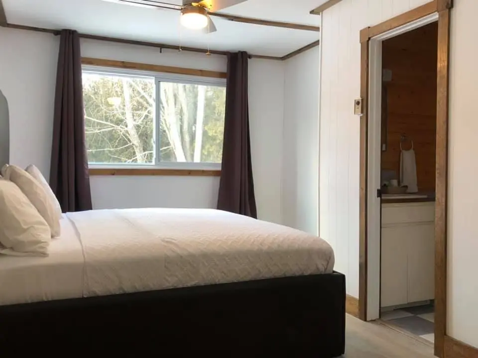 A king bed and window in a lodge room upstairs at Red Bay Lodge
