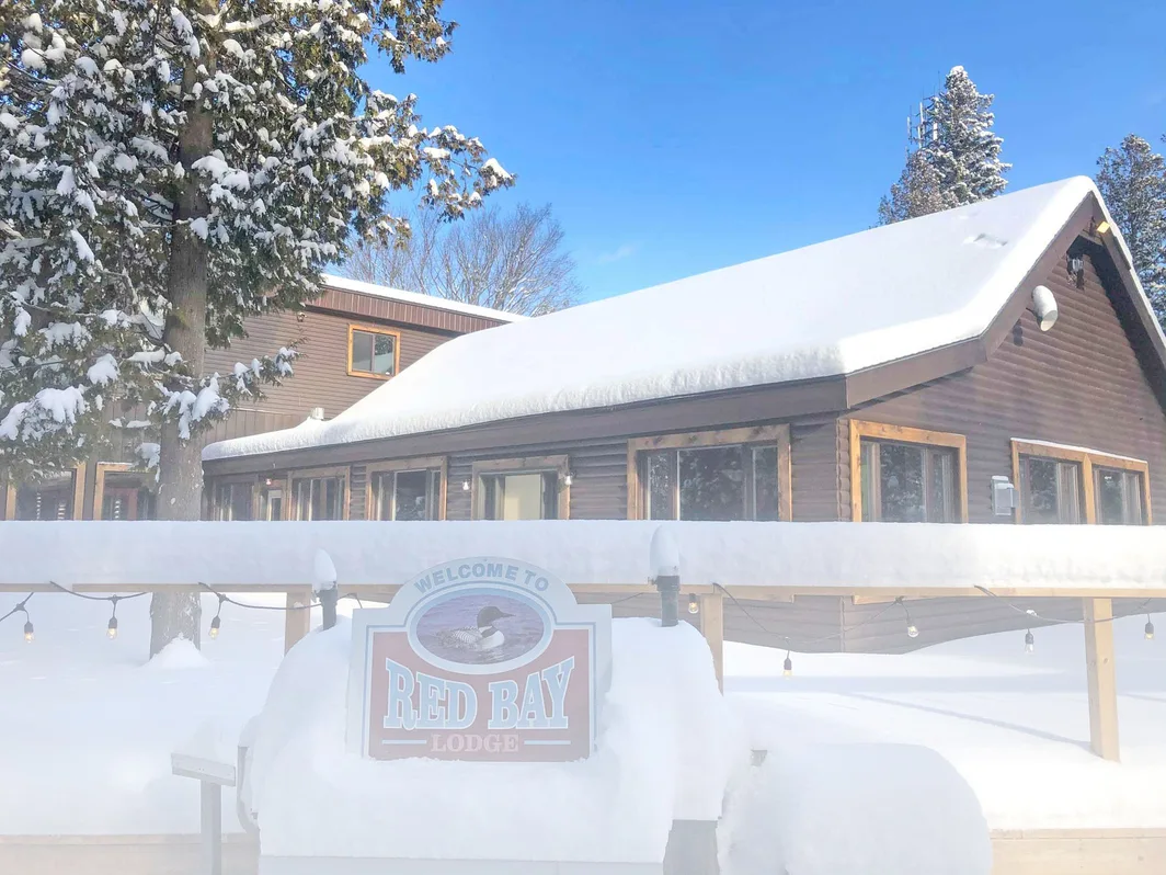 The Red Bay Lodge sign and the log-sided lodge under deep snow