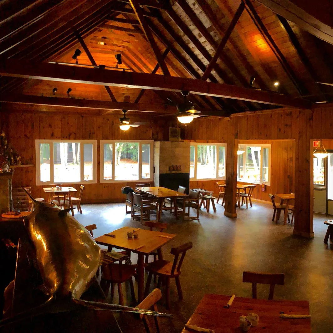 The Great Room at Red Bay Lodge: a high timbered ceiling, tall windows onto the trees and wooden tables
